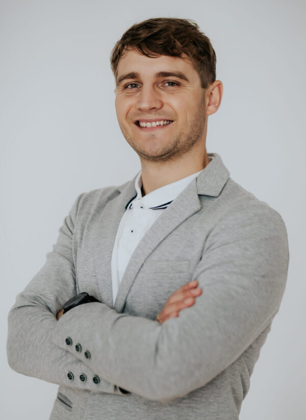 Mężczyzna, laureat programu stypendialnego UAM uśmiecha się.